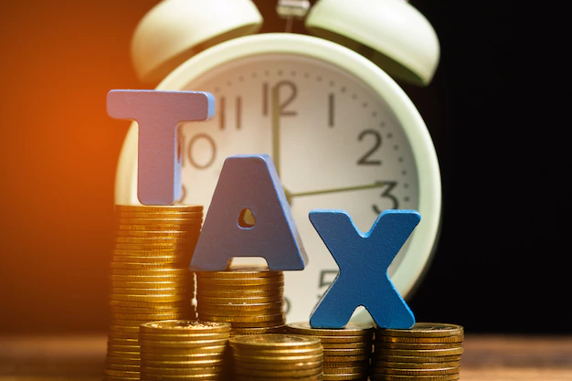 Tax alphabet with stack of coin and vintage alarm clock Premium Photo